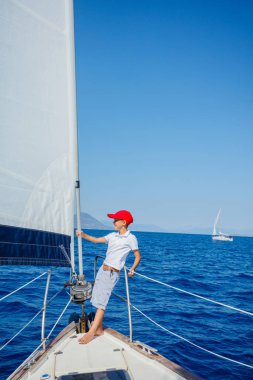 Küçük çocuk yaz gezisinde yelkenli yatında. Seyahat macerası, çocuğuyla yat gezisi..