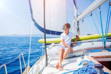 Little boy on board of sailing yacht on summer cruise. Travel adventure, yachting with child on family vacation. clipart