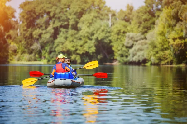 Mutlu çocuklar yaz tatilinde güneşli bir günde nehirde kano yapıyorlar. — Stok fotoğraf