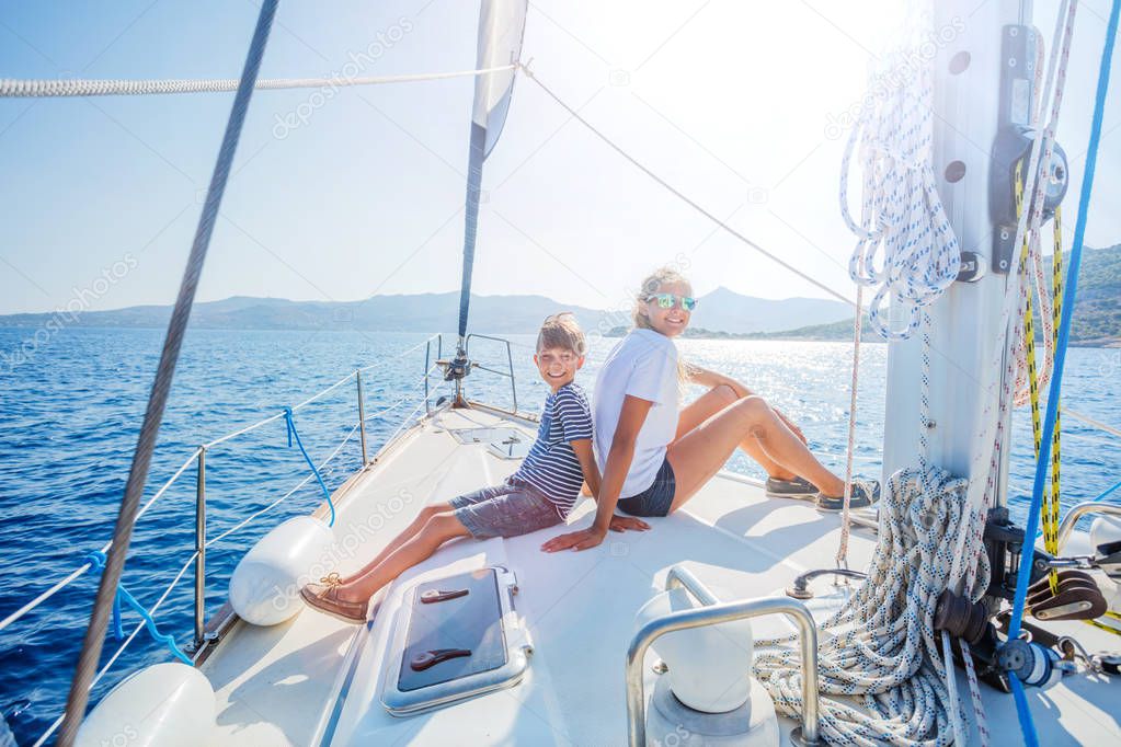 Boy with his sister on board of sailing yacht on summer cruise.