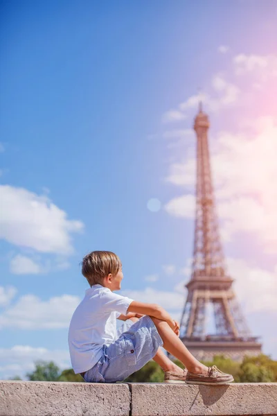 Chlapec seděl a díval se poblíž Eiffel tower — Stock fotografie