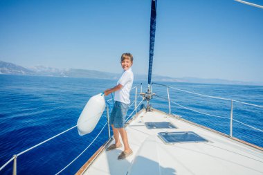 Little boy on board of sailing yacht on summer cruise. clipart
