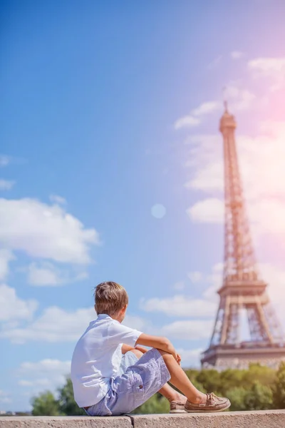 Junge sitzt am Eiffelturm und schaut zu — Stockfoto