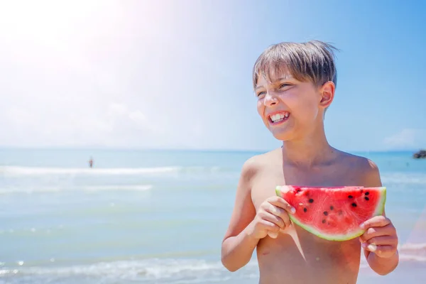 Portrét rozkošný chlapec s meloun na pláži. — Stock fotografie