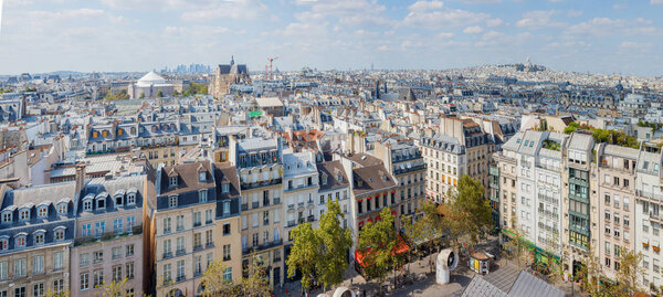 Classic Parisian buildings. Aerial view of roofs on a sunny day, with a blue sky. Cityscape view of Paris. Panorama