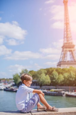Oğlum oturuyor ve aşağı izlerken Eyfel Kulesi yakınındaki