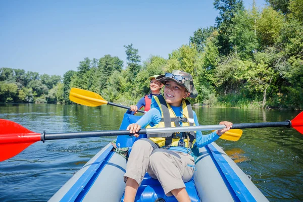 Mutlu çocuklar yaz tatilinde güneşli bir günde nehirde kano yapıyorlar. — Stok fotoğraf