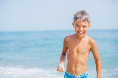 Boy having fun on tropical beach on suuny day clipart