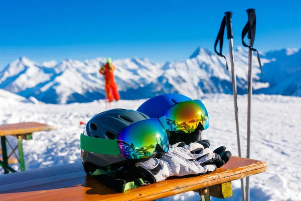 Colorful ski glasses, gloves and helmet on wooden table.