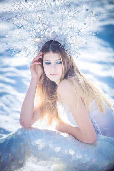 Jonge model in luxe strapless corset bal toga zittend op platen van gebroken ijs aan de frosty kust. Winter fairytale concept. — Stockfoto