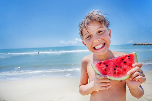 Портрет очаровательного мальчика с арбузом на пляже . — стоковое фото