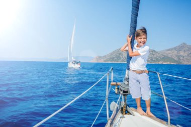 Küçük çocuk yaz gezisinde yelkenli yatında. Seyahat macerası, çocuğuyla yat gezisi..