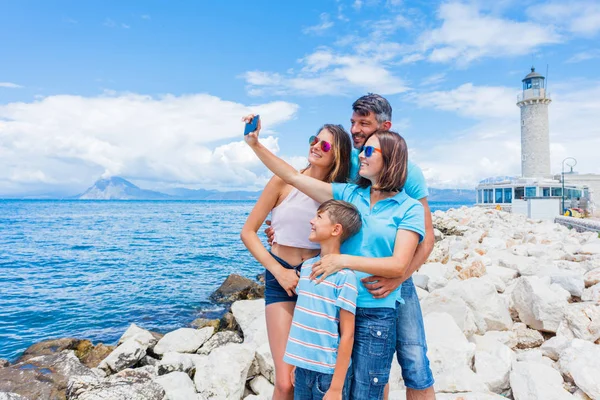 Familia feliz haciendo selfie frente al faro de Patras, Peloponeso, Grecia . — Foto de Stock