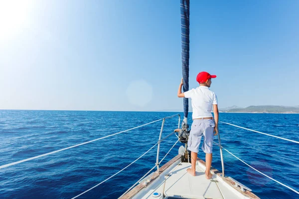 Menino a bordo do iate à vela no cruzeiro de verão. Viagem aventura, iatismo com criança em férias em família. — Fotografia de Stock