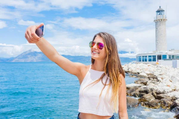 Щаслива дівчина прийняття selfie передній Патри Маяк, Пелопоннес, Греція. — стокове фото