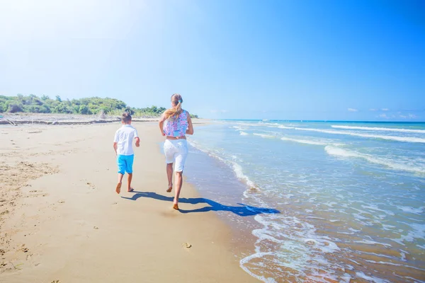 Vista trasera de los niños felices corriendo en la playa tropical —  Fotos de Stock