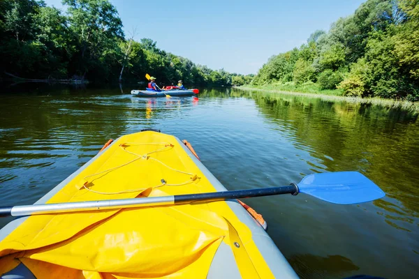 Mutlu çocuklar yaz tatilinde güneşli bir günde nehirde kano yapıyorlar.