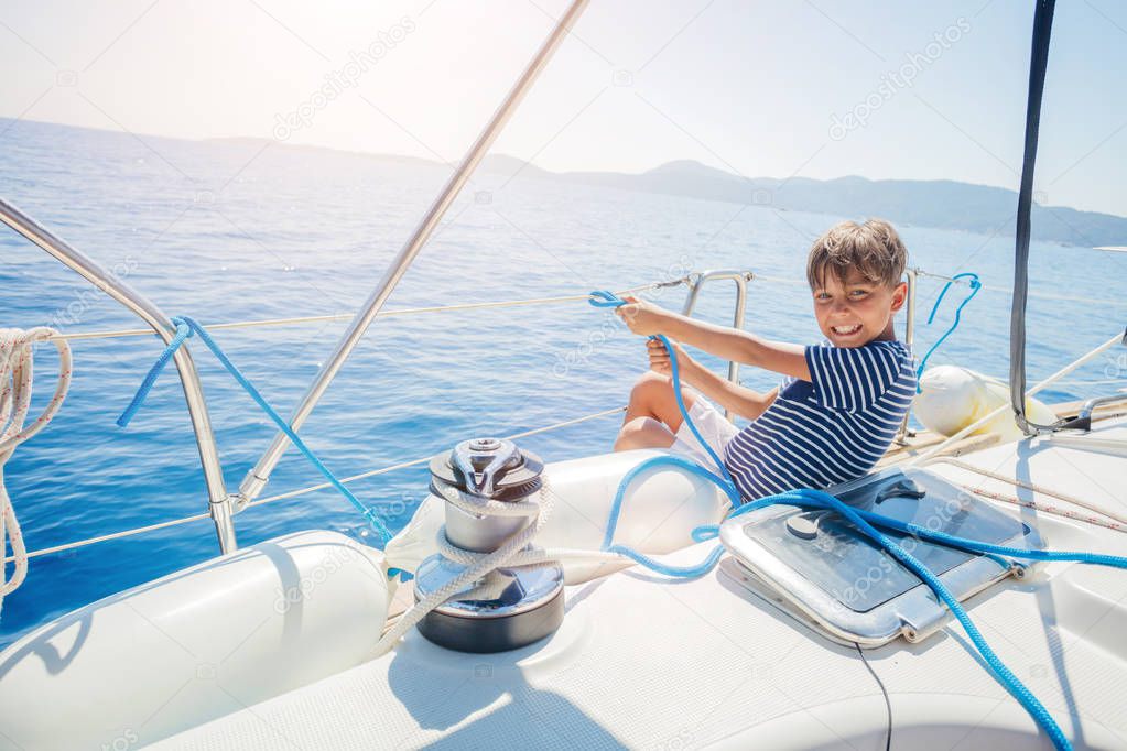 Little boy on board of sailing yacht on summer cruise. Travel adventure, yachting with child on family vacation.