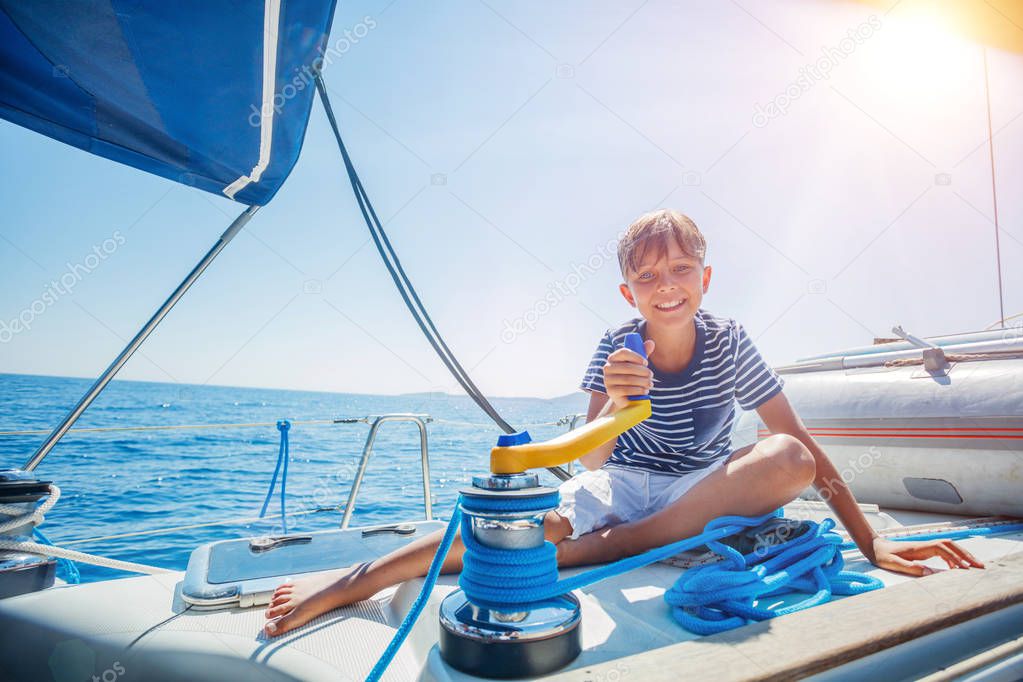 Little boy on board of sailing yacht on summer cruise. Travel adventure, yachting with child on family vacation.