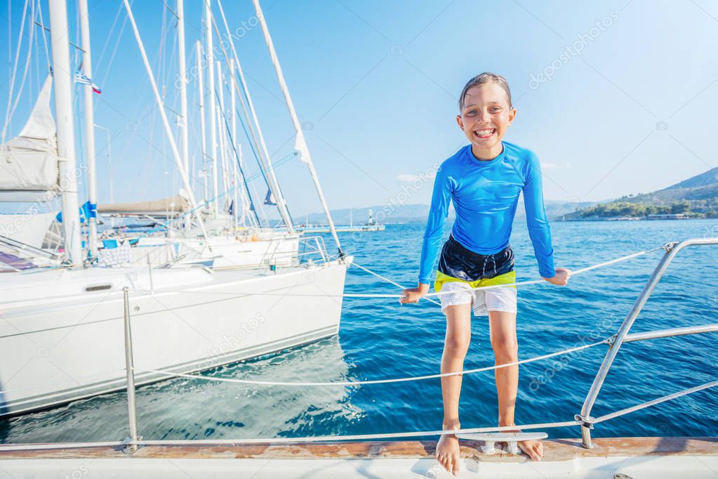 Little boy having fun on board of yacht on summer cruise. Travel adventure, yachting with child on family vacation.