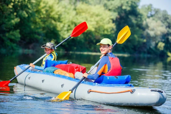 Gelukkige kinderen kajakken op de rivier op een zonnige dag tijdens de zomervakantie — Stockfoto