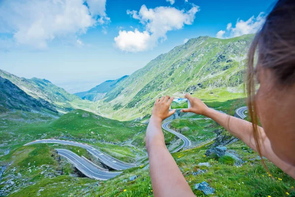 A menina tira uma foto da estrada da montanha Transfagarasan. Roménia . — Fotografia de Stock