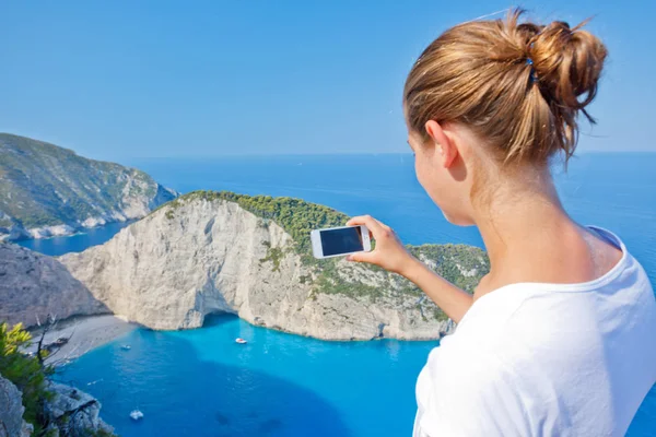 Chica haciendo foto con la bahía de Navagio y Ship Wreck playa en verano. El famoso hito natural de Zakynthos, isla griega en el mar Jónico —  Fotos de Stock