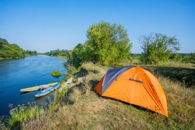 Kayak. Bir çadır kampı nehir kıyısında duruyor.