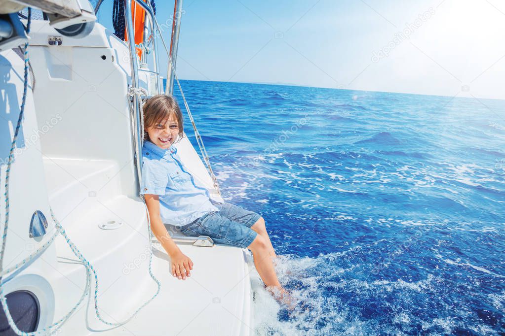 Little boy on board of sailing yacht on summer cruise. Travel adventure, yachting with child on family vacation.