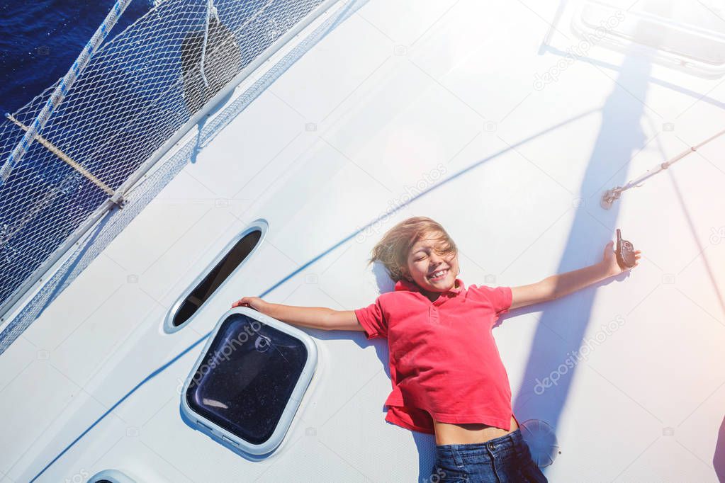 Little boy on board of sailing yacht on summer cruise. Travel adventure, yachting with child on family vacation.