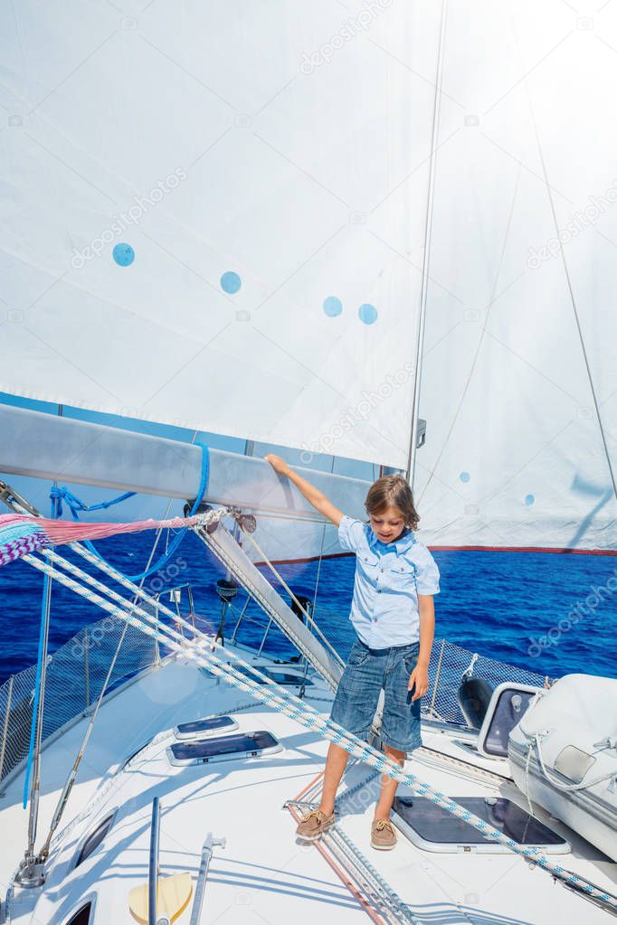 Little boy on board of sailing yacht on summer cruise. Travel adventure, yachting with child on family vacation.