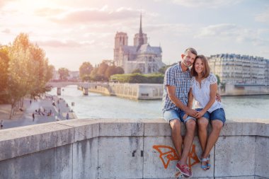 Mutlu çift Paris'te Notre-Dame katedrali yakınında sarılma. Fransa'da tatilin tadını çıkaran turistler. Romantik tarih veya seyahat çift kavramı