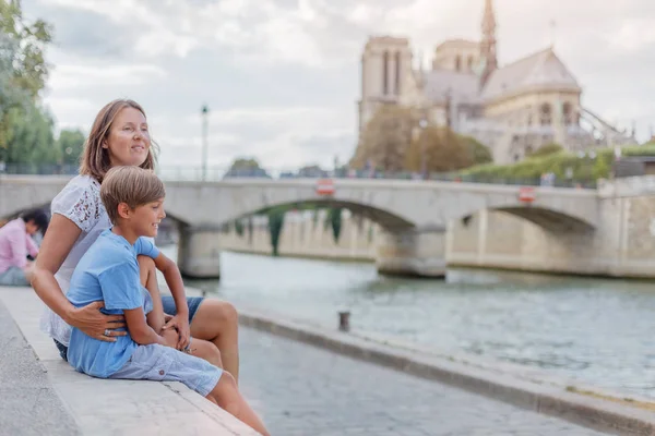 Gelukkige moeder en haar zoon die plezier hebben in de buurt van de kathedraal Notre-Dame in Parijs. Toeristen genieten van hun vakantie in Frankrijk. — Stockfoto