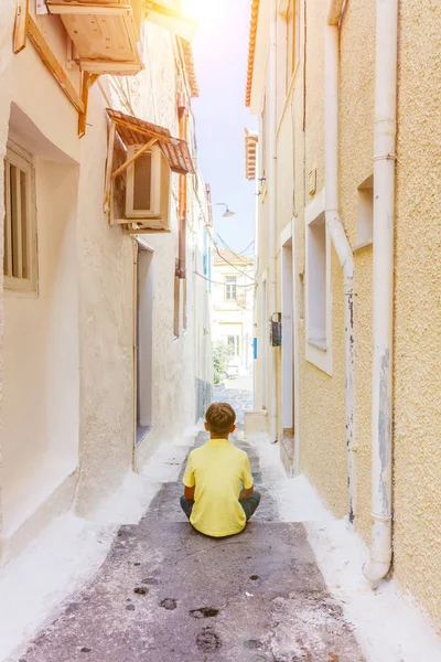 在希腊克里特岛老希腊镇的台阶上，可爱的男孩的后视图。夏季景观 — 图库照片