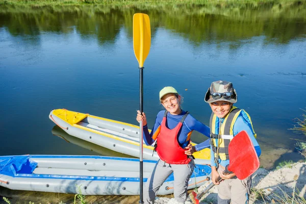 Gelukkige kinderen kajakken op de rivier op een zonnige dag tijdens de zomervakantie — Stockfoto