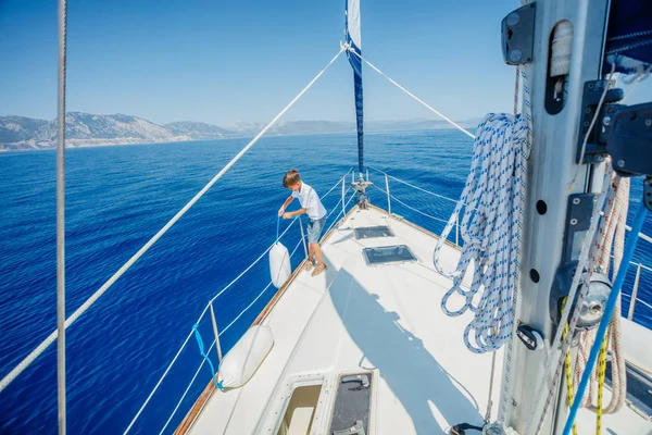 Ragazzino a bordo di yacht a vela in crociera estiva. Avventura di viaggio, yachting con bambino in vacanza in famiglia. — Foto Stock