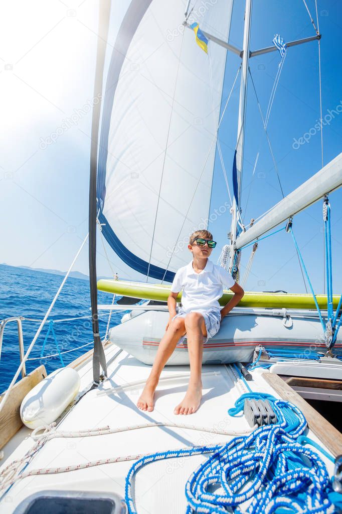 Little boy on board of sailing yacht on summer cruise. Travel adventure, yachting with child on family vacation.