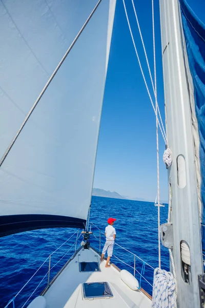 Menino a bordo do iate à vela no cruzeiro de verão. Viagem aventura, iatismo com criança em férias em família. — Fotografia de Stock