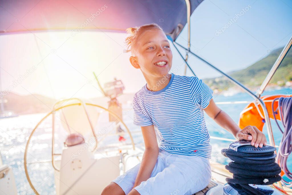 Little boy on board of sailing yacht on summer cruise. Travel adventure, yachting with child on family vacation.