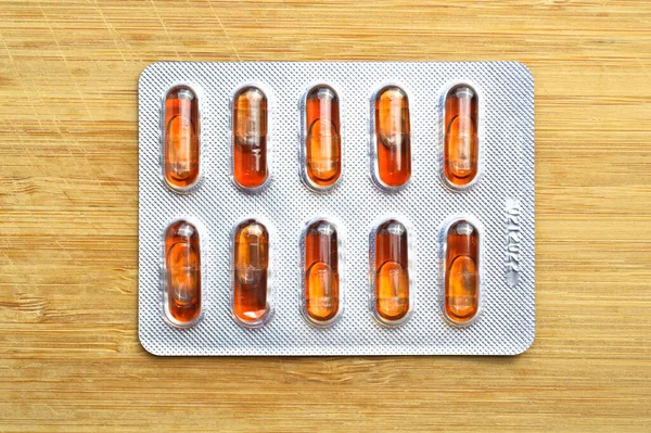 Pomarańczowa Kapsułka Tabletki Izolowane Tle Drewna Kapsułki Medyczne Pigułki — Zdjęcie stockowe