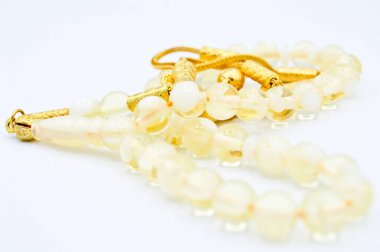 Beyaz ve altın boncuklar sıralı, kısa tespih tesbih, Türk kültürü için önemli bir aksesuar, beyaz arka planda izole edilmiş.