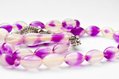 Mor ve gümüş boncuklar sıralı, kısa tespih tesbih, Türk kültürü için önemli bir aksesuar, beyaz arka planda izole edilmiş.