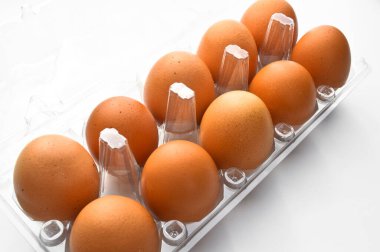 Plastik bir pakette taze organik kahverengi yumurtalar, beyaz arka planda izole edilmiş.