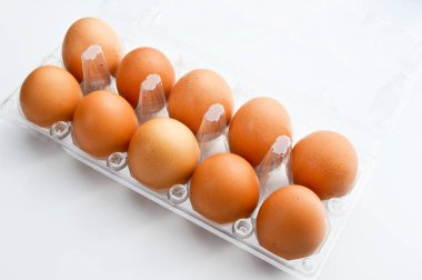 Plastik bir pakette taze organik kahverengi yumurtalar, beyaz arka planda izole edilmiş.