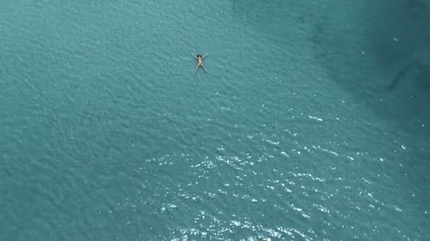 Hermosa mujer joven flotando en aguas cristalinas, tiro giratorio aéreo — Vídeos de Stock