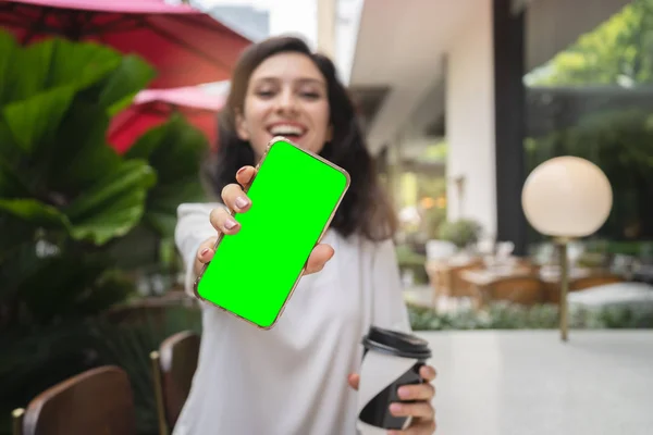 Молода жінка показує сучасний золотий смартфон з зеленим екраном для заміни — стокове фото
