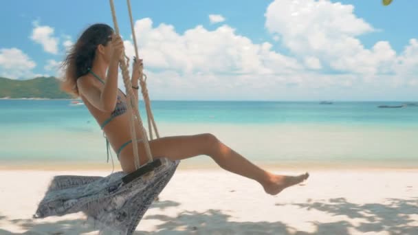 Schöne junge Frau auf einer Schaukel am Strand — Stockvideo