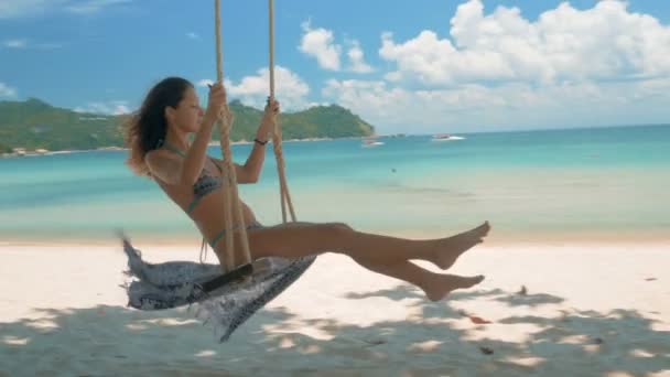 Bella giovane donna su un'altalena sulla spiaggia. 4k loop — Video Stock