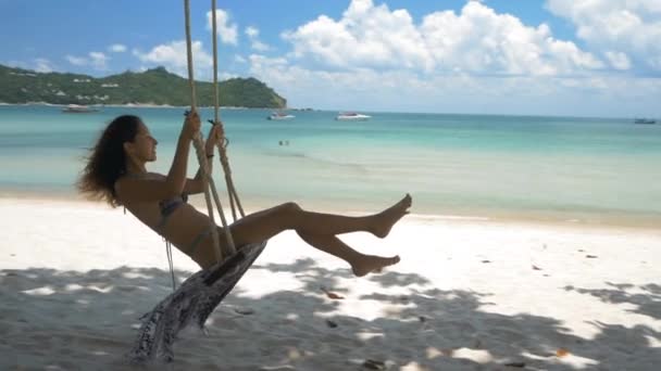 Mooie jonge vrouw op een schommel op het strand in slow motion — Stockvideo