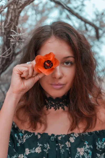 Młoda kobieta posiadający pomarańczowy kwiat na jej oko — Zdjęcie stockowe